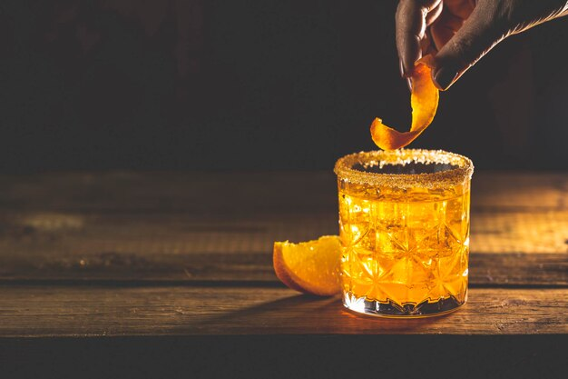 Hand garnishing a cocktail in a wine glass with a lime slice.